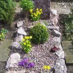 Grab-Gestaltung mit Natursteinen und Polsterpflanzen